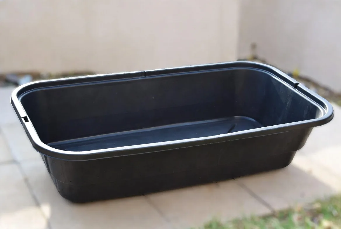 A broad black watertight container suitable for a small wildlife pond
