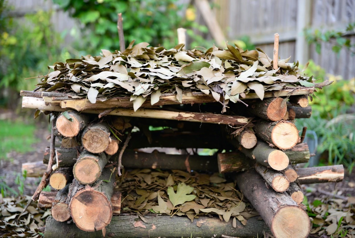 A finished log and leaf habitat built from stacked branches and leaf litter
